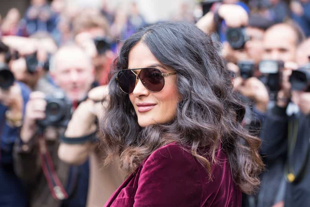 The actress Salma Hayek was at the Stella McCartney fashion show in Paris last October 2, 2017. She was seen wearing a red velvet outfit, a confident smile and tousled curly hair with highlights.