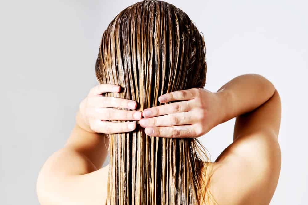 Woman applying hair conditioner.