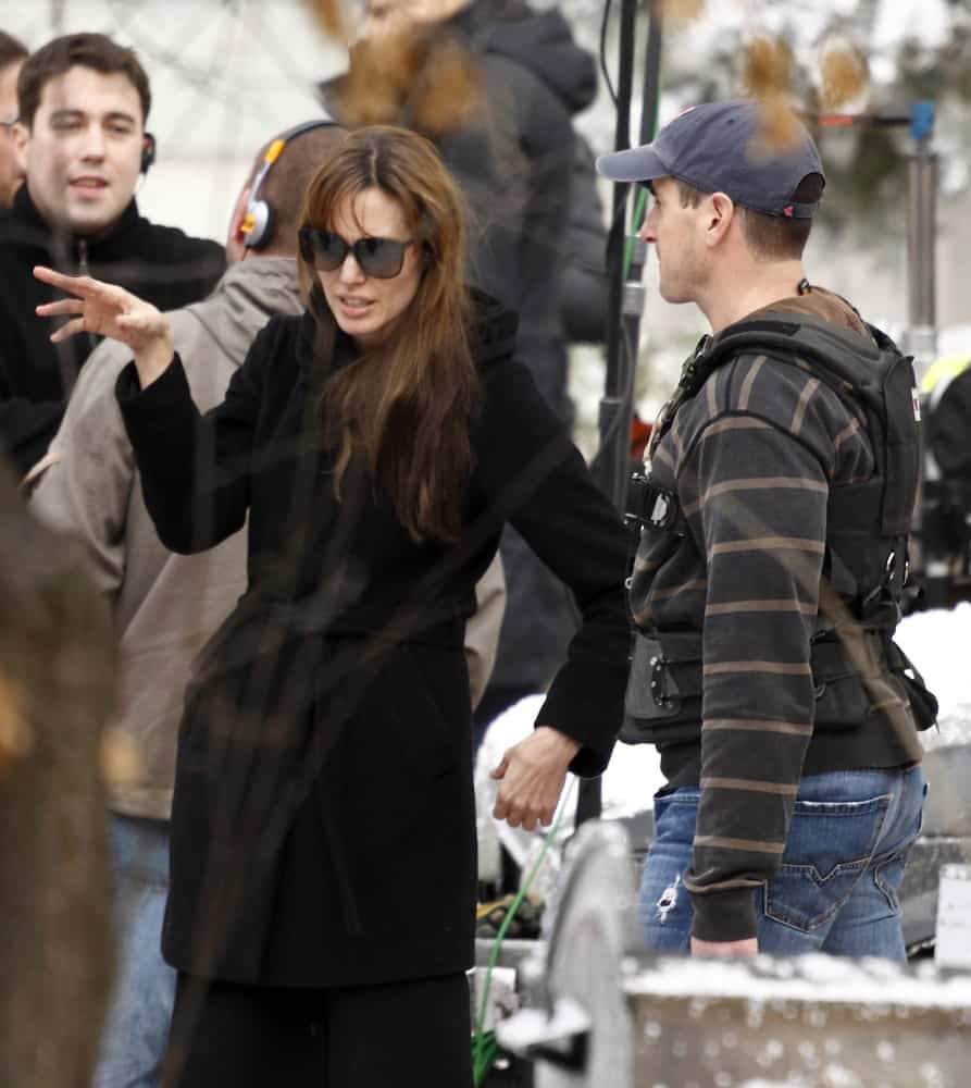 Angelina Jolie wore a large black winter coat with her loose and tousled hairstyle that has bangs and highlights at her movie shooting in the 9th District on November 9, 2010 in Budapest, Hungary.