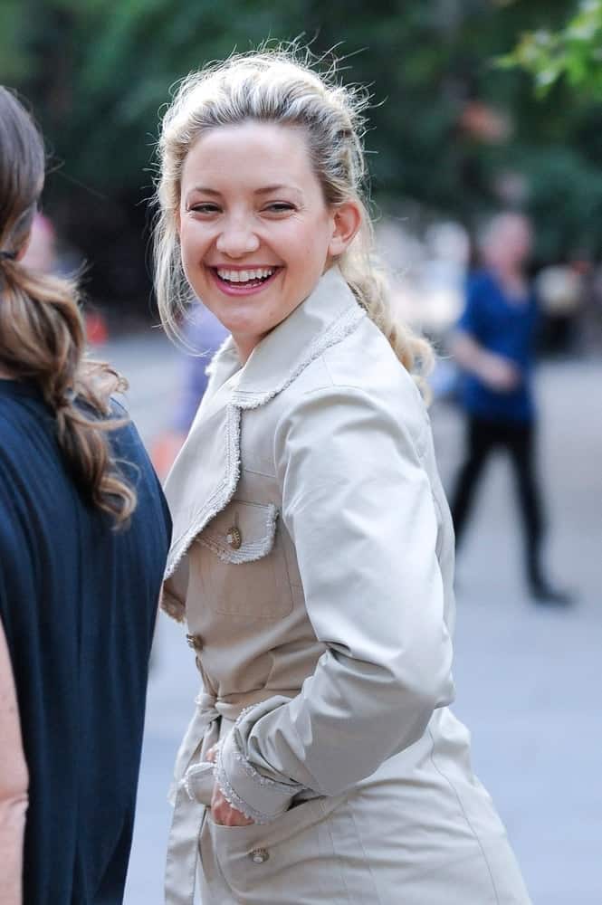 Kate Hudson was seen at the 'Something Borrowed' movie set in New York, NY on June 2, 2010. She was wearing a trench coat with her bright smiles and messy low ponytail hairstyle with loose blond tendrils.