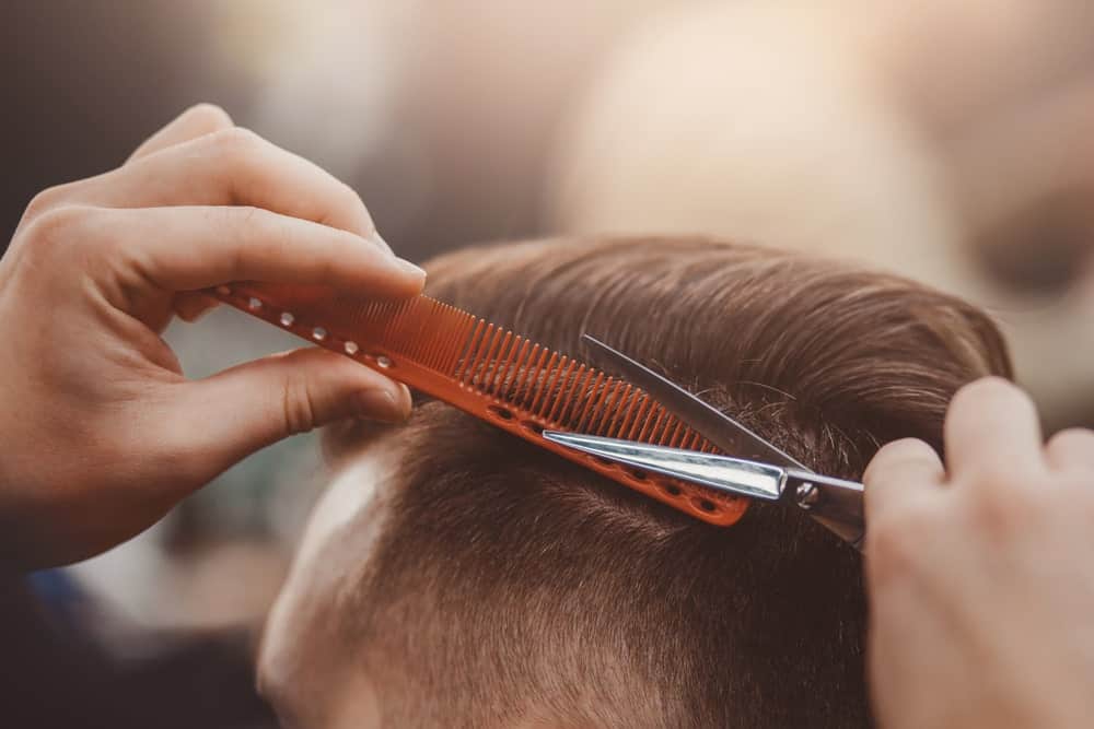 A close look at a barber comb being used in a barber shop.