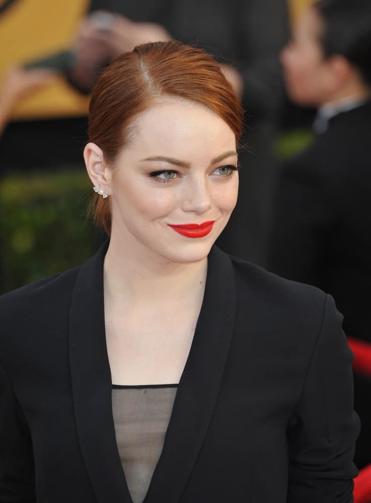 On January 25, 2015, Emma Stone's bold red lips stood out with her confident smile, black outfit and slick low bun hairstyle at the 2015 Screen Actors Guild Awards at the Shrine Auditorium.