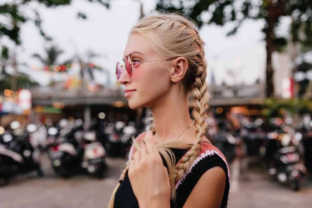 Woman with blonde braided hair in pink sunglasses.