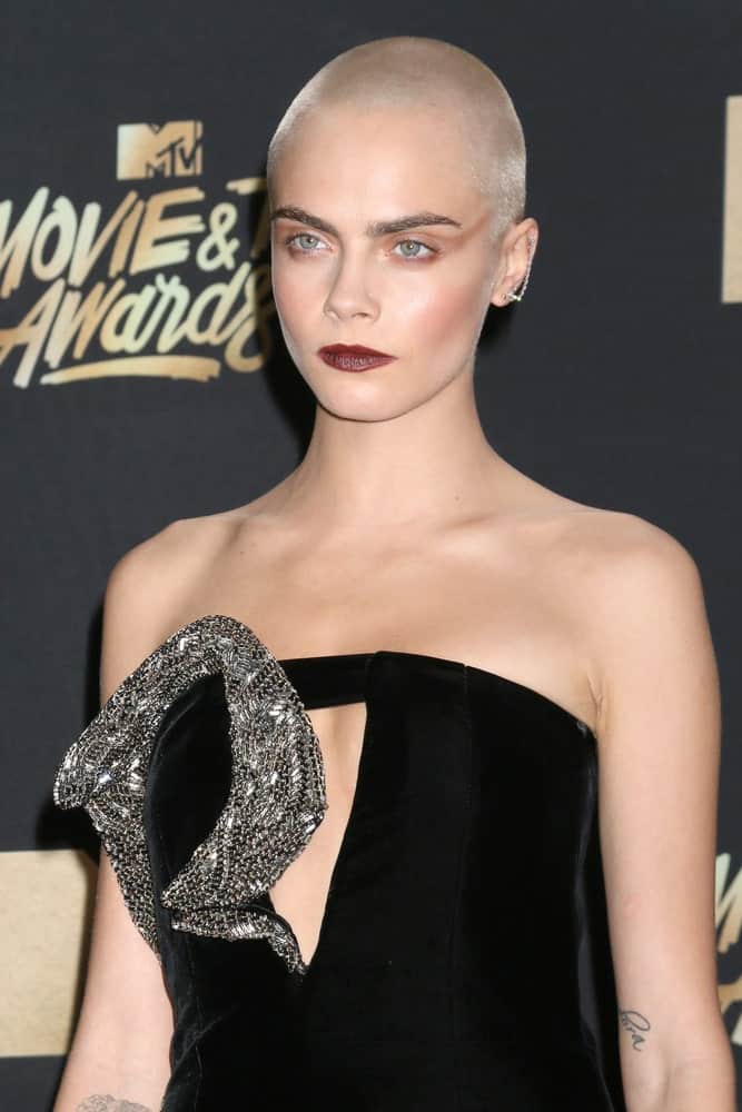 Cara Delevingne went with an edgy platinum blond buzz cut to go with her bold make-up and black dress at the MTV Movie and Television Awards on the Shrine Auditorium on May 7, 2017 in Los Angeles, CA.