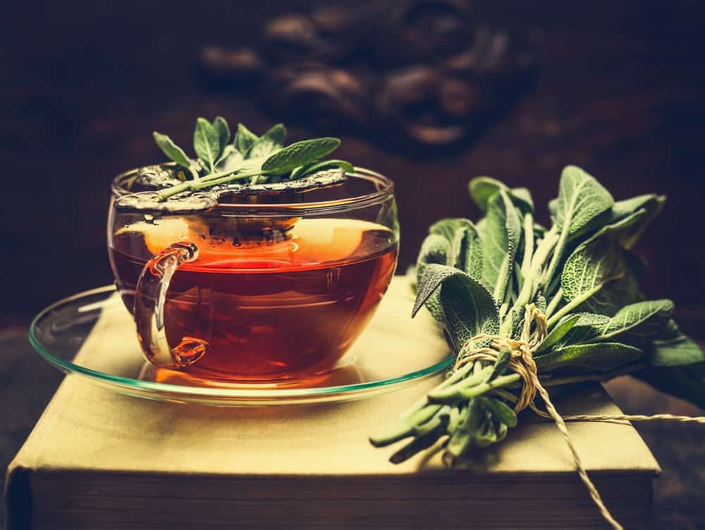 Sage extract on a cup along with its leaves.