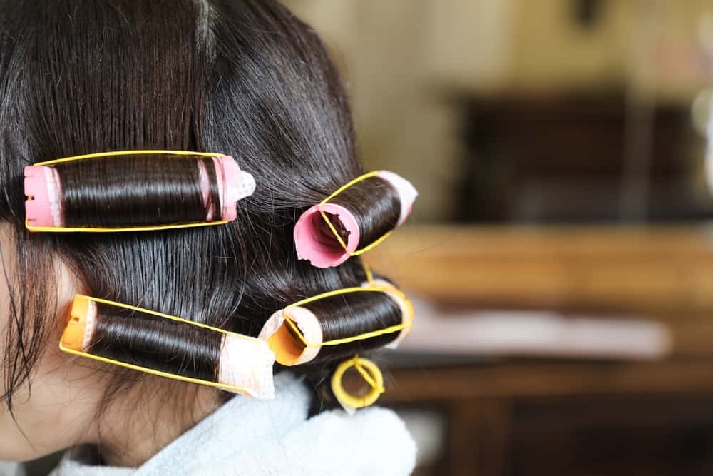 A girl with her dark hair in rollers.