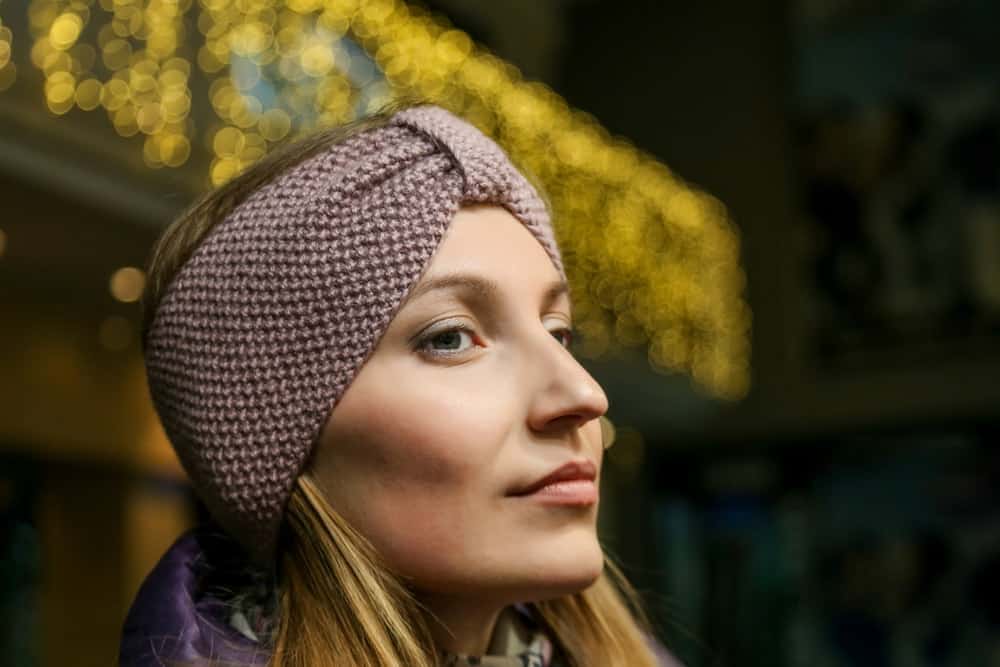 A close look at a woman wearing a brown knit headband.