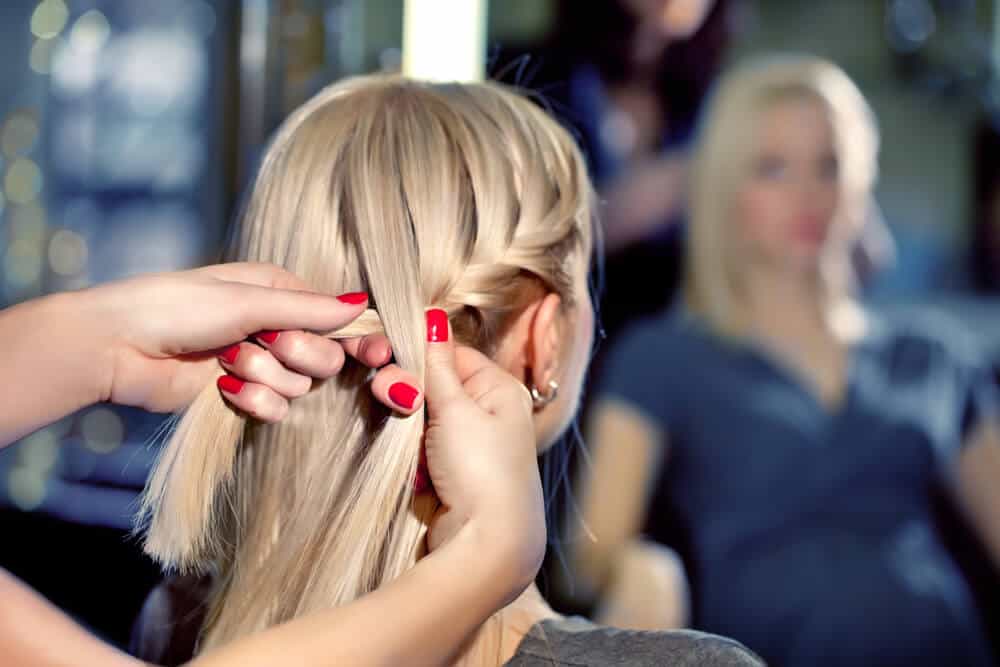 A woman with straight blonde hair gets a French braid.