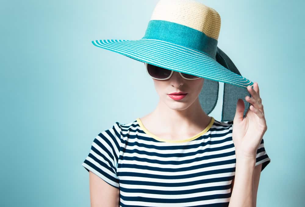 Woman in stripe wearing a green sun hat.