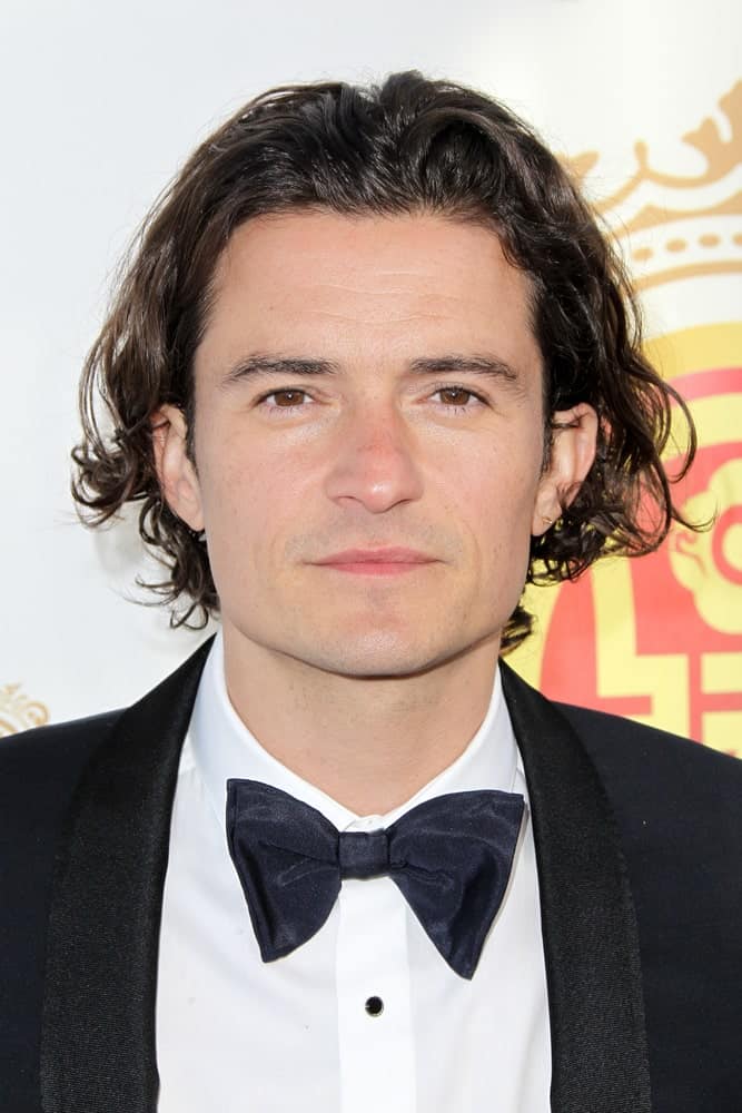 Actor Orlando Bloom's long and dark curls are on full display with his gorgeous smile and classy tux at the 2014 Huading Film Awards at The Montalban in Hollywood, California.