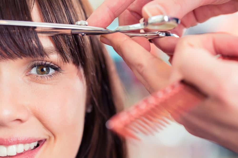 A close look at a woman having her bangs cut.