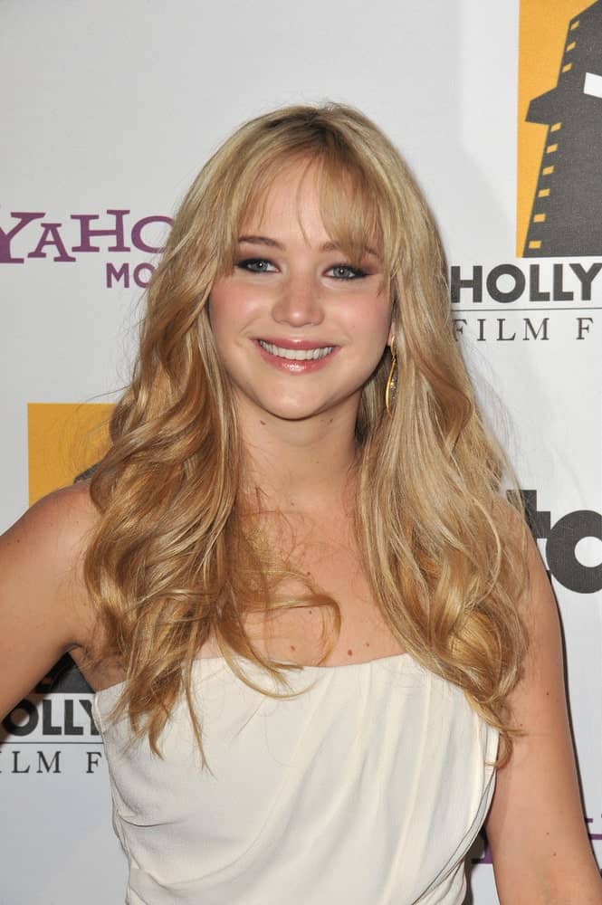 Jennifer Lawrence's long, layered and highlighted sandy blond hair was complemented with wispy bangs and a white strapless dress at the 14th Annual Hollywood Awards Gala at the Beverly Hilton Hotel on October 25, 2010 in Beverly Hills, CA.