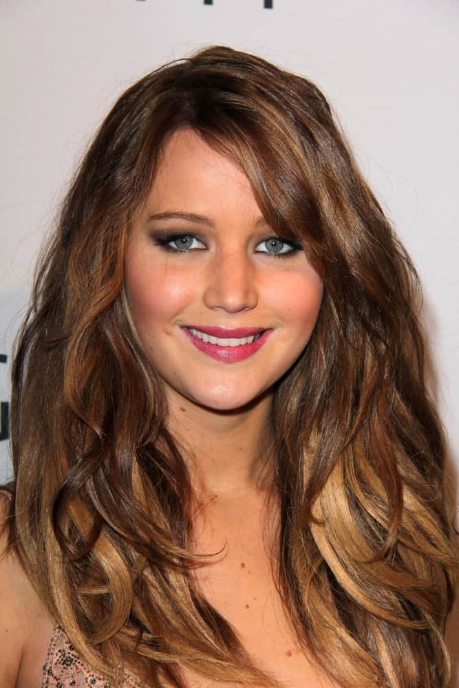 Jennifer Lawrence had a long, loose, tousled and layered hairstyle with side-swept bangs at the Hollywood Reporter Celebrates the 85th Academy Awards Nominees event at the Spago on February 4, 2013 in Beverly Hills, CA.