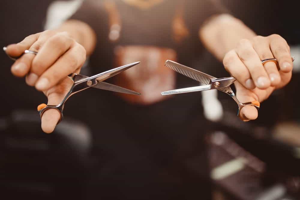 A barber holding two pairs of scissors.