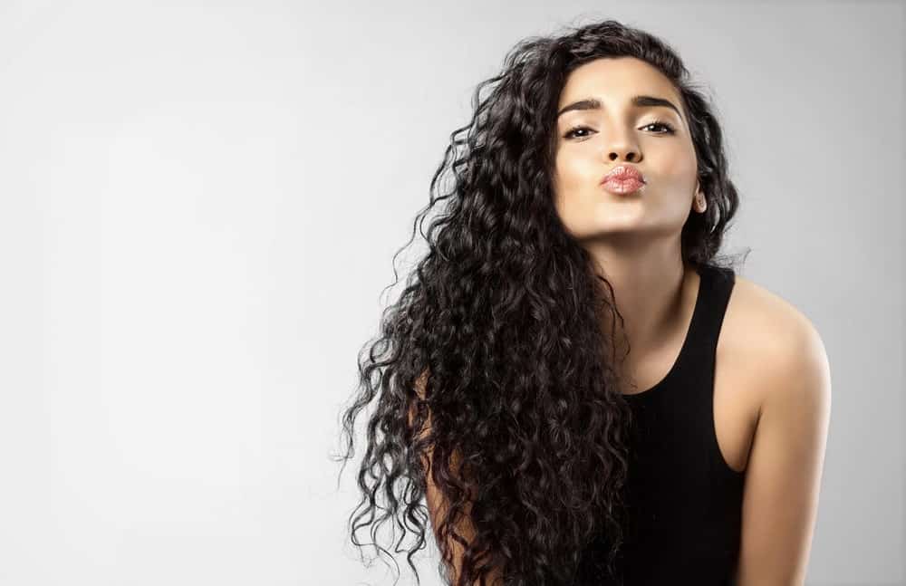 Beautiful woman with dark curly hair pouts at the camera.