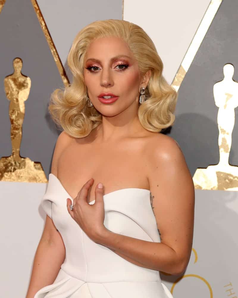 Lady Gaga attended the 88th Annual Academy Awards at the Dolby Theater on February 28, 2016 in Los Angeles, CA. She paired her lovely white strapless dress with a vintage look on her white blond hair that was styled into side-swept large curls.