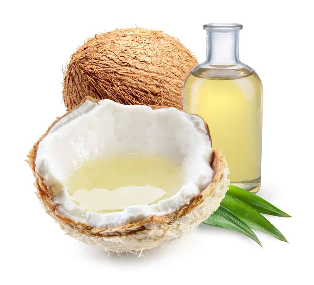 A bottle of coconut oil along with fresh nuts.