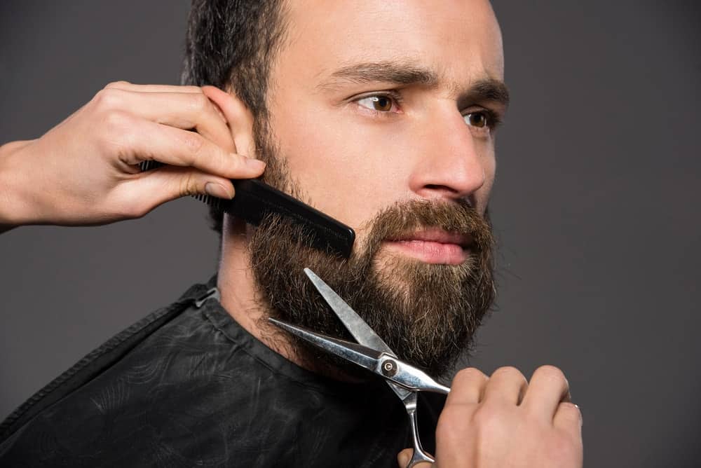 A man having his beard trimmed by a barber.