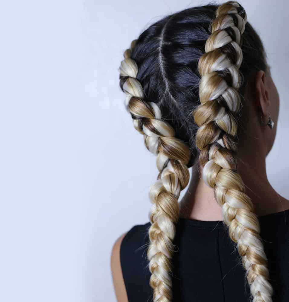 A woman with two large braids as seen from behind.