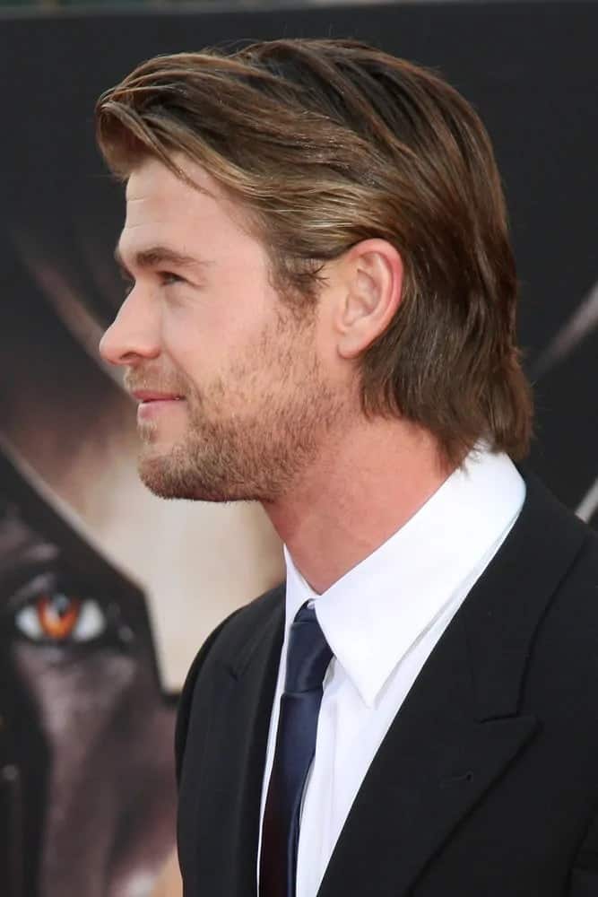 Chris Hemsworth paired his classic black suit and navy blue tie with a mid-length layered and highlighted side swept hairdo at the Empire Film Awards 2012.