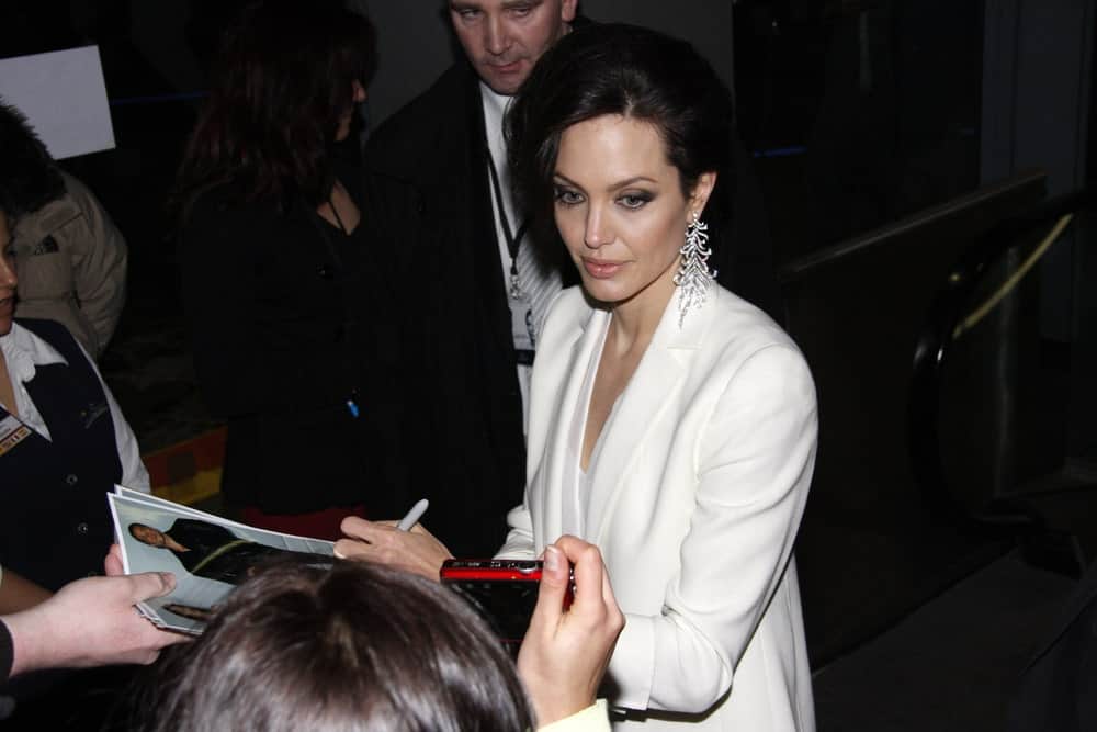 Angelina Jolie was quite fashionable in her white elegant outfit and side-swept half up tousled hairstyle to emphasize her earrings at the German premiere of The Curious Case of Benjamin Button at the Sony Center CineStar on January 19 2009 in Berlin.