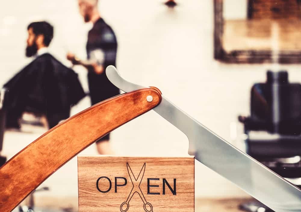 An "open" sign in front of a barbershop salon.