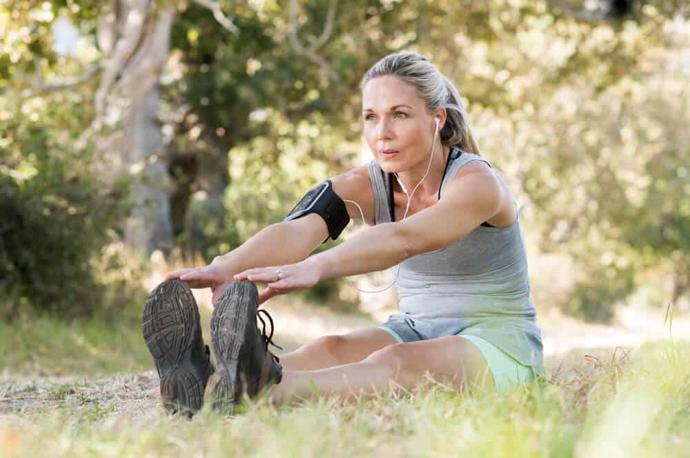 An elder woman doing an exercise outdoors.