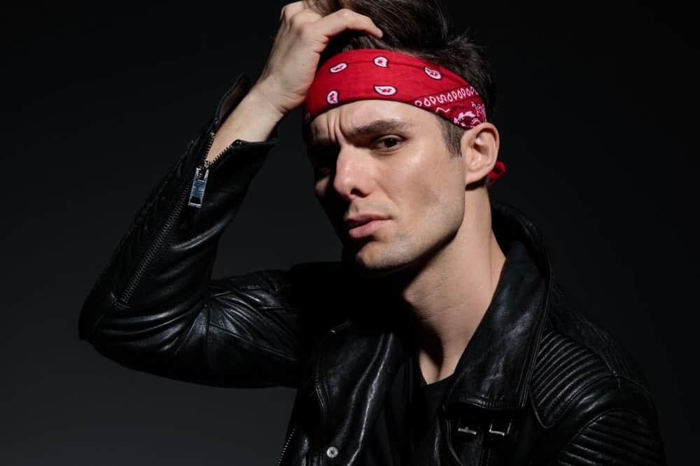 A man wearing a black leather jacket and a bandana headband.