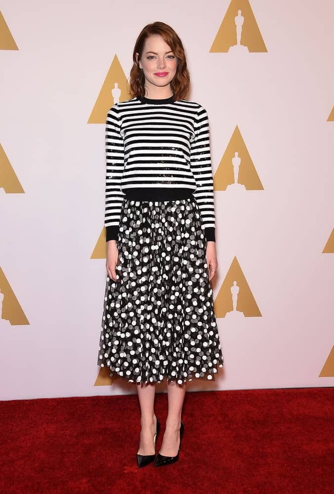 Emma Stone went for a simple yet lovely look with her black and white ensemble outfit that went quite well with her sweet make-up and loose side-swept waves at the Oscar Nominee Reception on February 2, 2015 in Beverly Hills, CA.