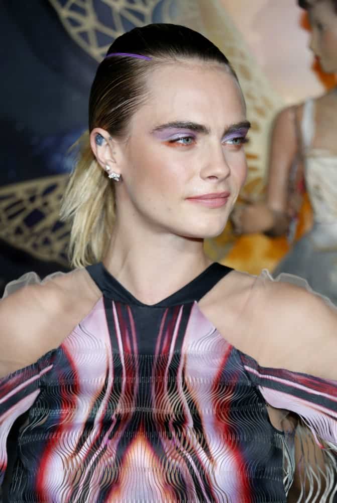 Cara Delevingne wore an elegant colorful dress to pair with her colorful make-up and multi-colored, slick ponytail hairstyle at the Los Angeles premiere of Amazon's 'Carnival Row' held at the TCL Chinese Theatre in Hollywood, USA on August 21, 2019.