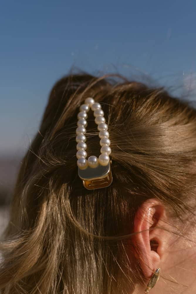 A woman wearing a barrette adorned with pearls.