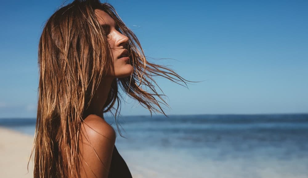 Woman with a loose, brown hair on the beach.