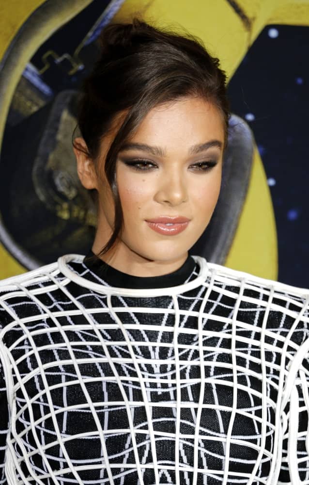 Hailee Steinfeld shows off a neat upstyle hairstyle complemented by a wavy tendril that falls down her cheek at the World premiere of 'Bumblebee' held on December 9, 2018.  It was completed with a trendy black dress that perfectly suited the theme.