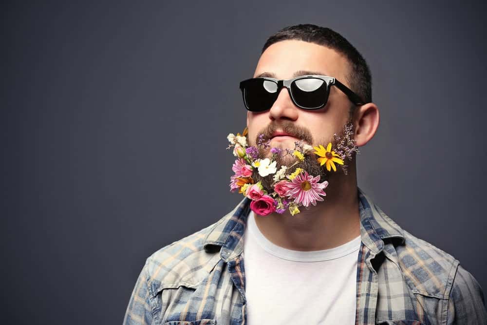 Man in sunglasses with beard of flowers.