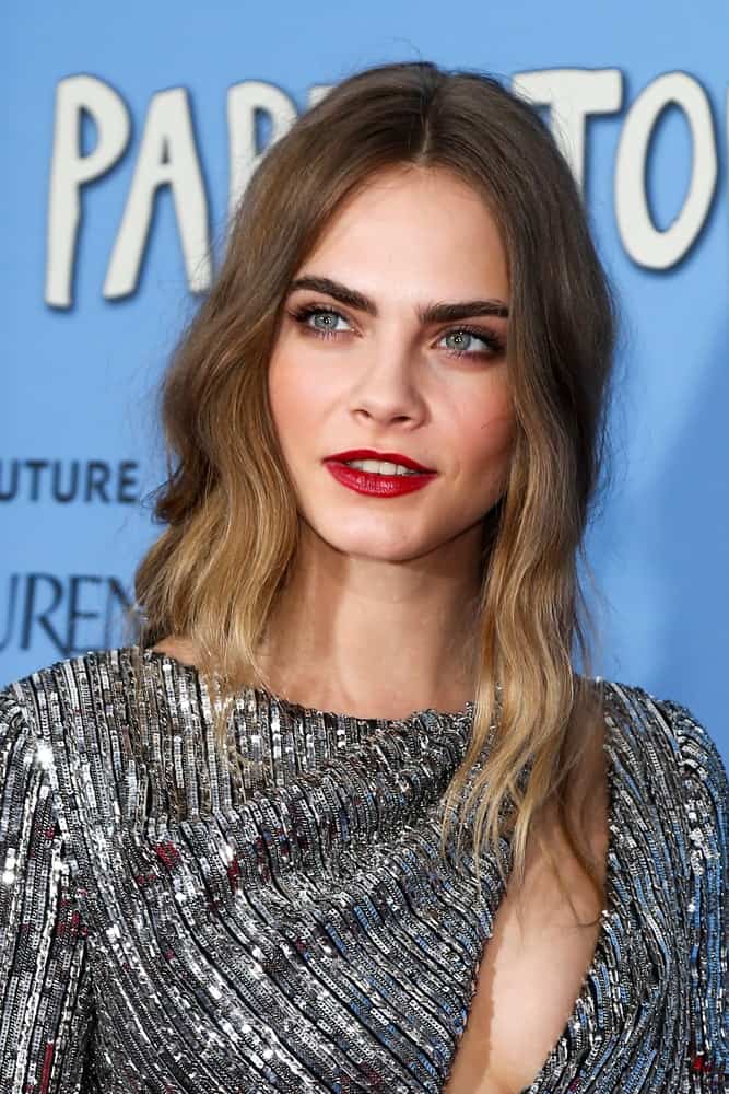 Model/actress Cara Delevingne attended the "Paper Towns" premiere at AMC Loews Lincoln Square on July 21, 2015 in New York City. She was stunning in her silver glittery dress that she paired with an asymmetrical hairstyle that has highlights and waves.