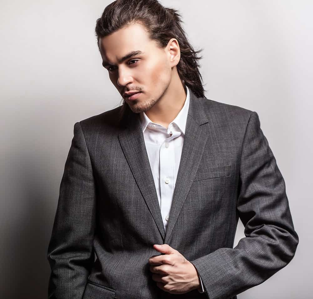 Young man rocks a ponytail hairstyle with a tuxedo.