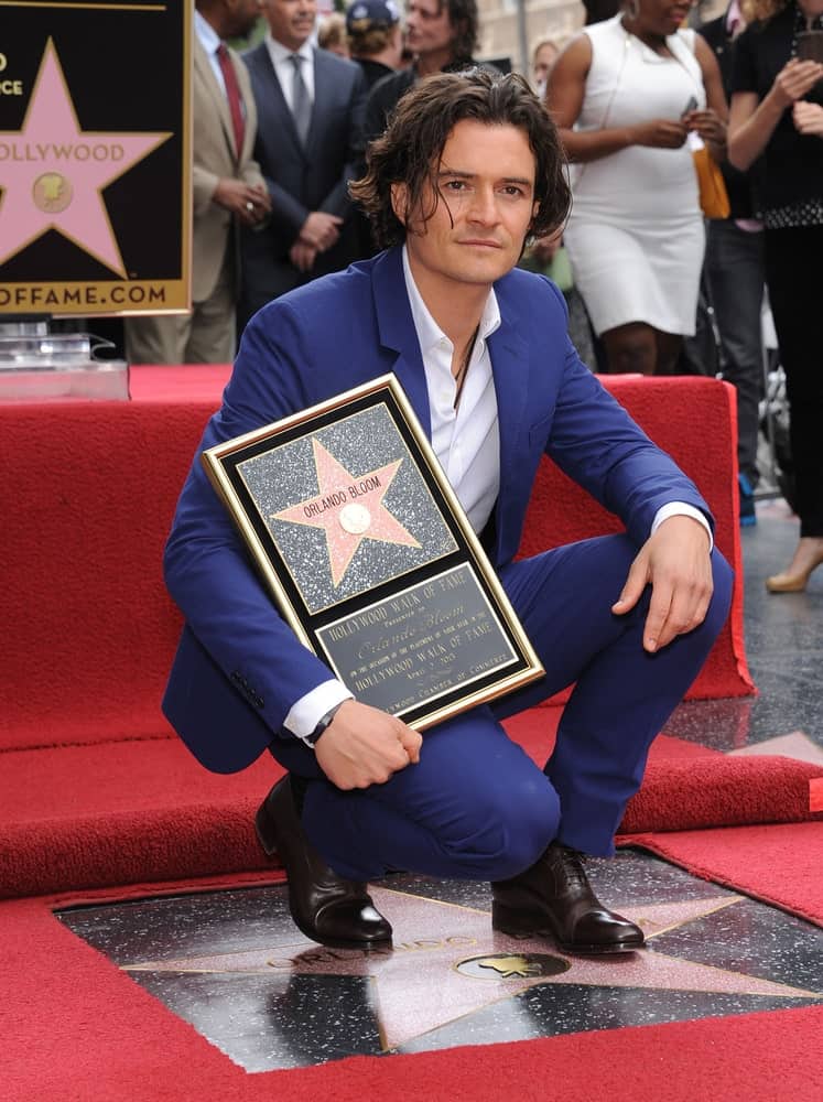 Orlando Bloom was honored at the Walk of Fame on April 02, 2014 in Hollywood, CA. He was brimming with pride in his blue suit that matches well with his long and wavy center-parted hairstyle.