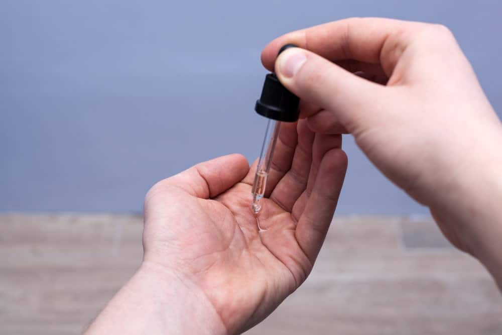 Man dripping beard oil into his palm from a pipette.