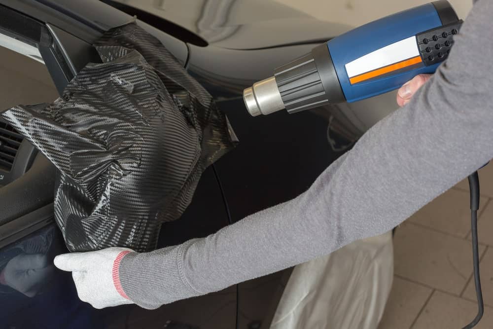 Heat Gun Vs Hair Dryer. A heat gun being used to laminate a side mirror.