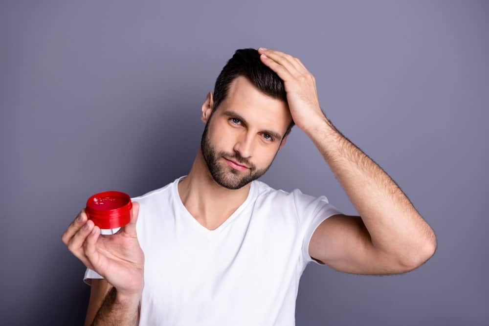 Man applying hair wax to his black hair.