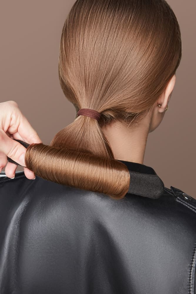 A woman wearing a bun and crown shaper on her brunette hair.