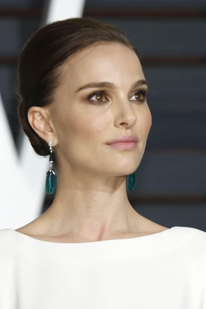 Natalie Portman's slick low bun hairstyle was perfectly matched with her green earrings and white dress at the Vanity Fair Oscar Party 2015 at the Wallis Annenberg Center for the Performing Arts on February 22, 2015 in Beverly Hills, CA.