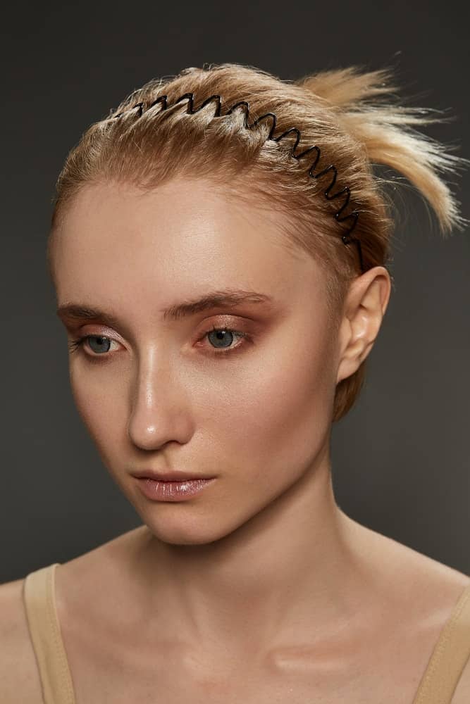 A woman wearing a thin and black wavy headband.