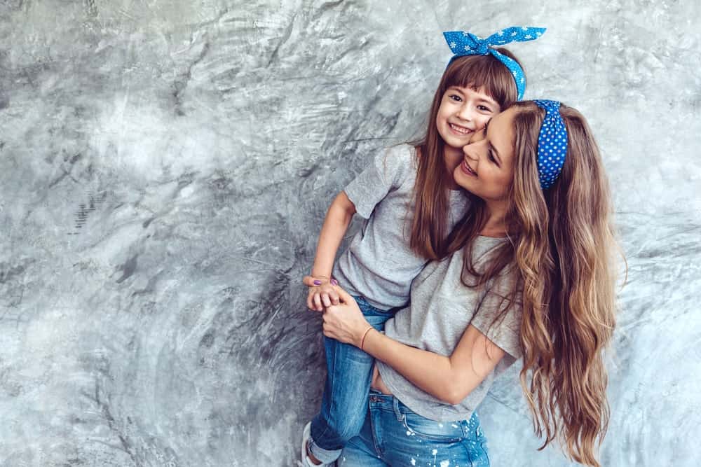 A mother and her daughter wearing matching outfits and headbands.