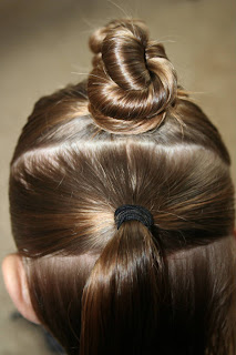 Back view of young girl's hair being styled into "The Bun-Hawk" hairstyle