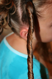 Side view of young girl's hair being styled into "4 Messy-Pigtail Twists" hairstyle