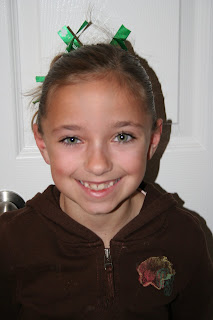 Portrait view of young girl modeling "Messy Bun" hairstyle styled with green ribbon hair accessory