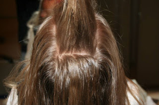 Back view of young girl's hair being styled into "Top-Knot with Banded" Ponytail