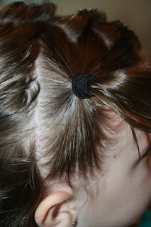 Side view of a young girl's hair being styled into “Heart Pigtail” hairstyle