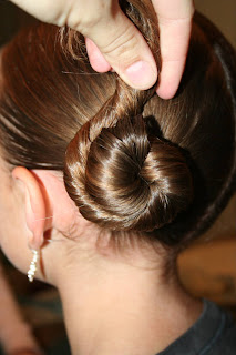 Side view of young girl's hair being styled into "Basic Twisty Buns" hairstyle